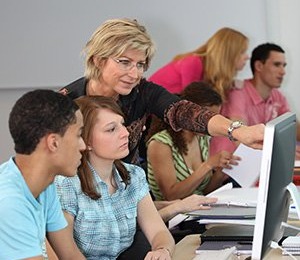 Teacher helping students in a computer lab.