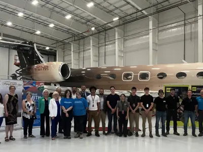 group of students standing in front of a plane