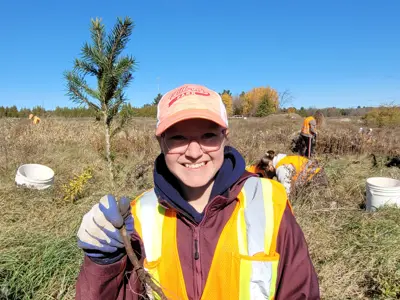 student holding up a sapling